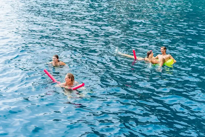Guests swimming with floats in clear blue water on a Capri boat tour